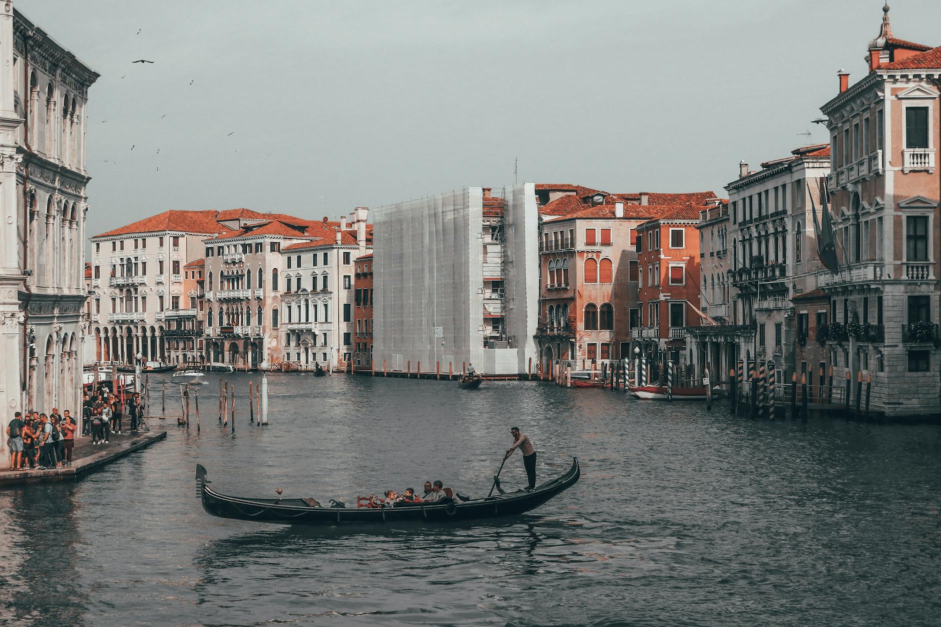 unrecognizable people in gondola on canal between old urban houses